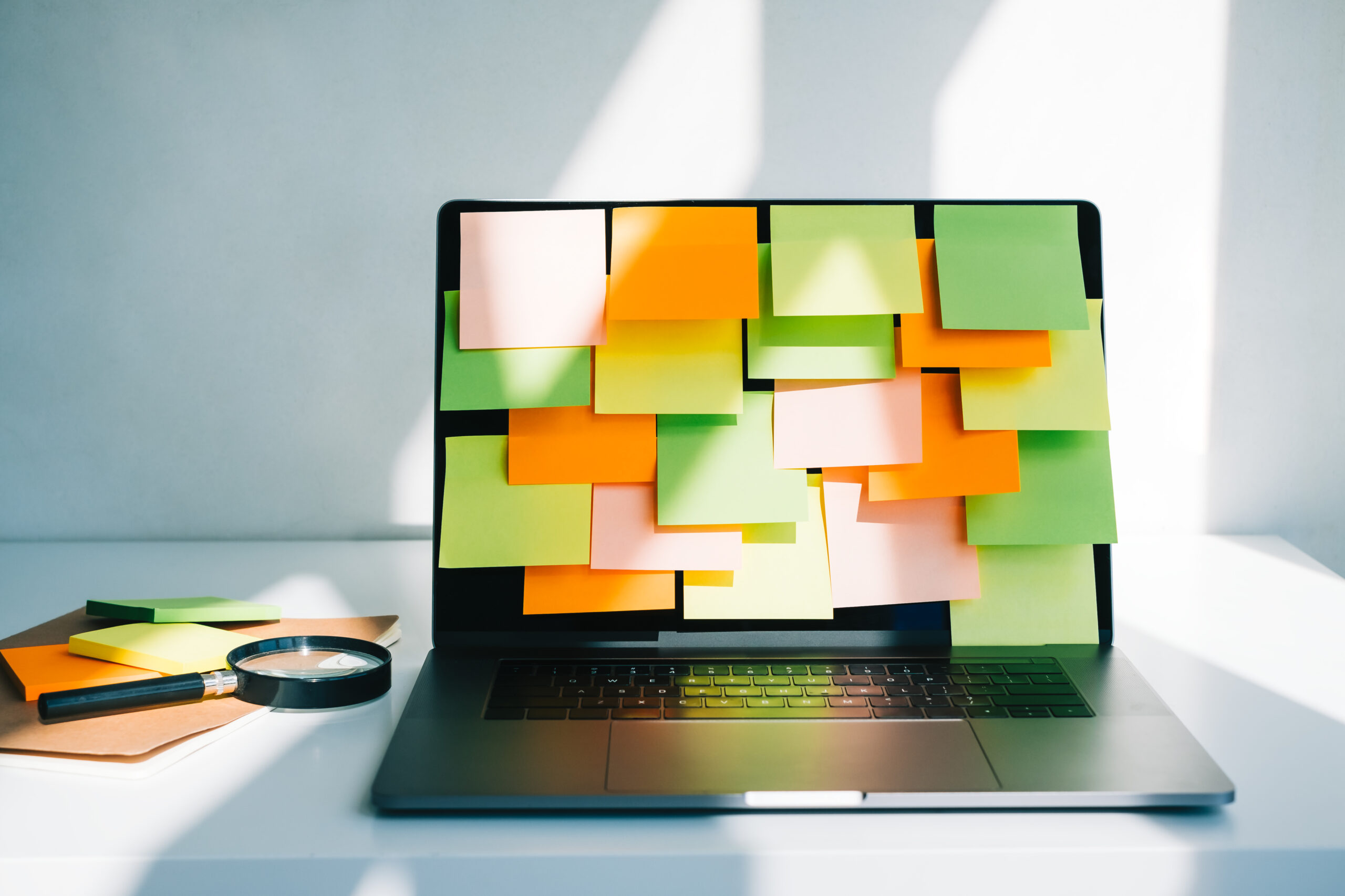 Workplace with laptop computer with many colorful empty sticky notes on display.